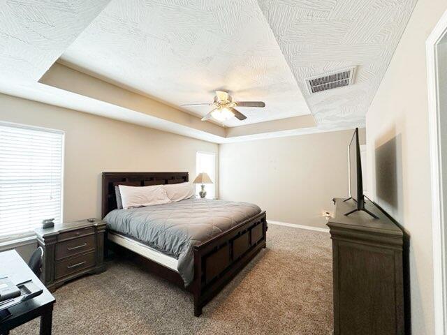 bedroom featuring a tray ceiling, carpet floors, and a textured ceiling