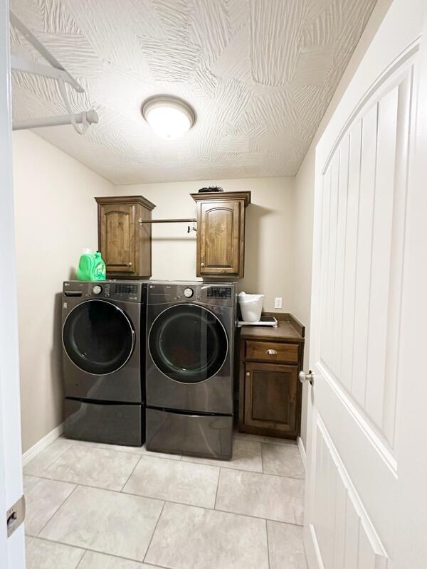 laundry area with light tile patterned floors, separate washer and dryer, and cabinets