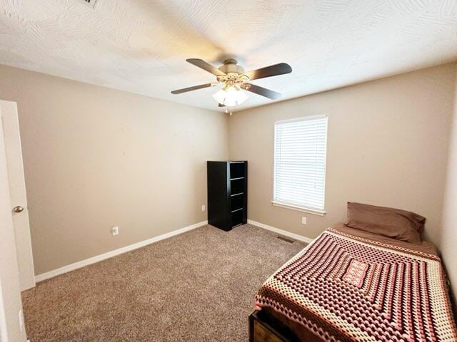 bedroom featuring light carpet, ceiling fan, and a textured ceiling