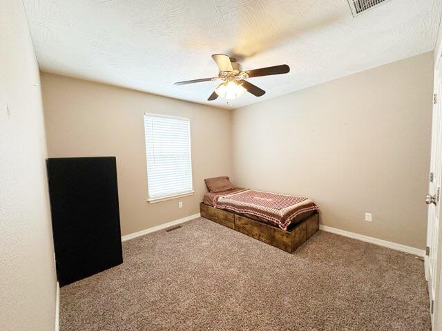 carpeted bedroom with a textured ceiling and ceiling fan