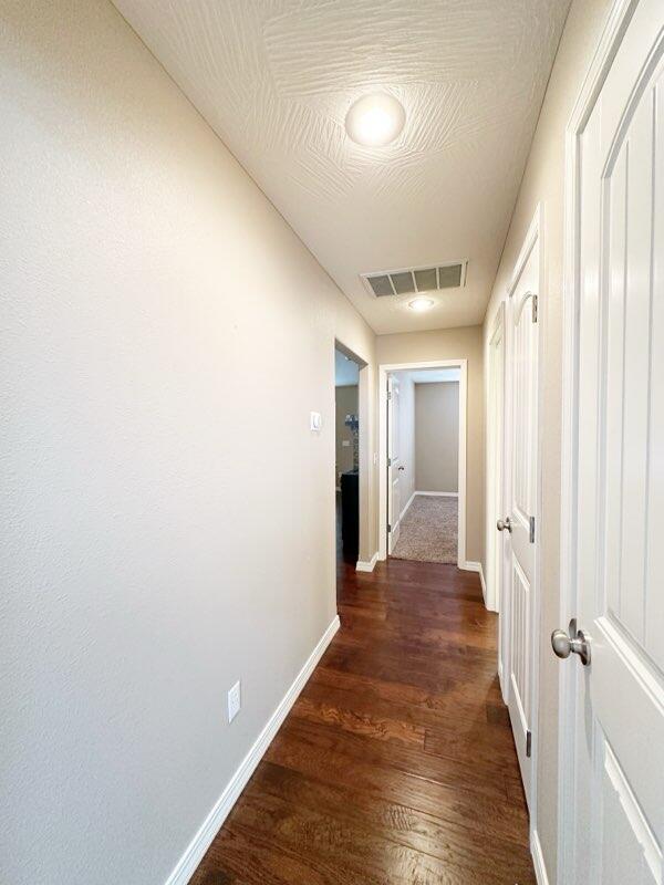 hallway with dark hardwood / wood-style floors and a textured ceiling