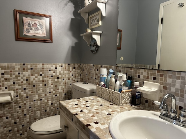 bathroom with tile walls, toilet, and vanity