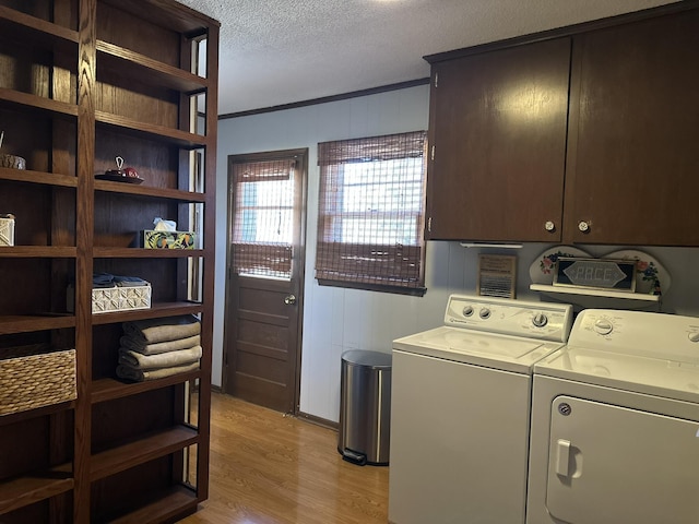 washroom with cabinet space, light wood finished floors, crown molding, a textured ceiling, and separate washer and dryer