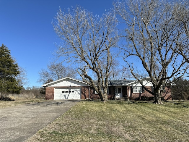 single story home with driveway, brick siding, a chimney, an attached garage, and a front yard