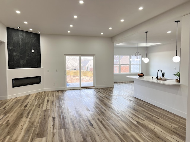 unfurnished living room featuring a fireplace, light hardwood / wood-style flooring, sink, and an inviting chandelier