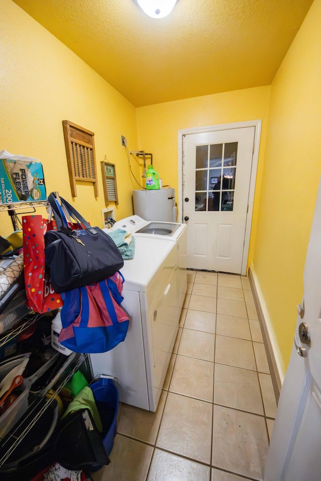 laundry room with light tile patterned floors, independent washer and dryer, water heater, and a textured ceiling