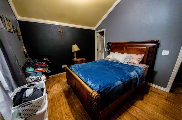 bedroom with lofted ceiling, hardwood / wood-style floors, and crown molding