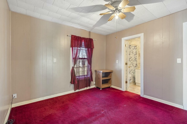 carpeted empty room featuring ceiling fan and baseboards