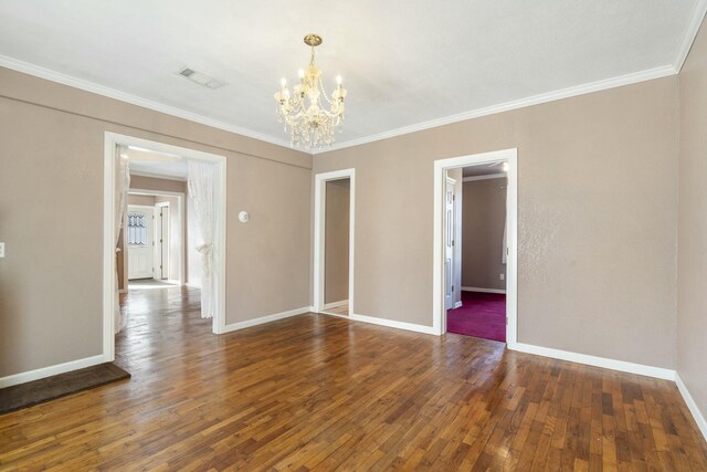 empty room featuring visible vents, baseboards, ornamental molding, dark wood-style flooring, and a chandelier