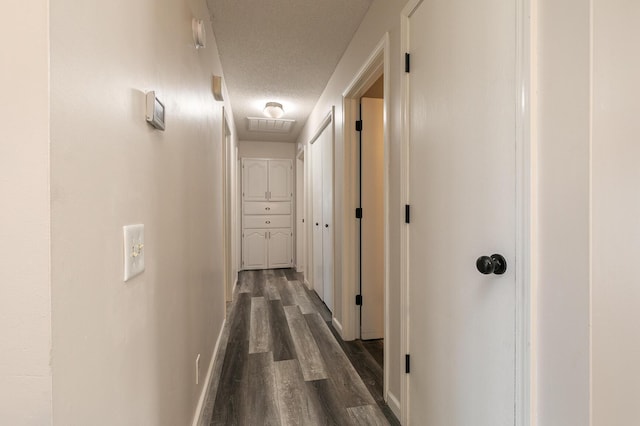 hallway with a textured ceiling and dark hardwood / wood-style flooring