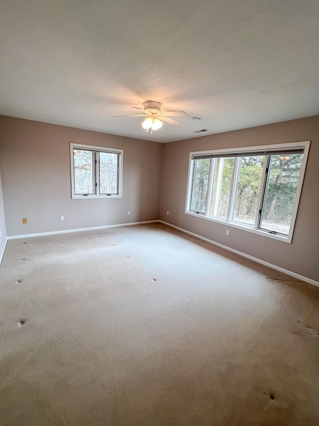 carpeted spare room featuring ceiling fan and a healthy amount of sunlight