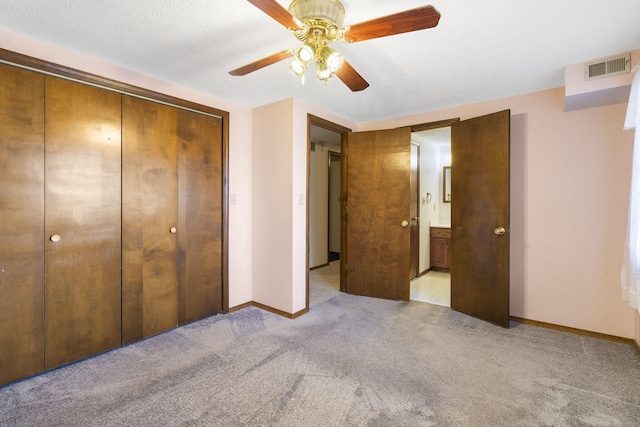 unfurnished bedroom featuring ceiling fan, ensuite bath, light carpet, and a closet