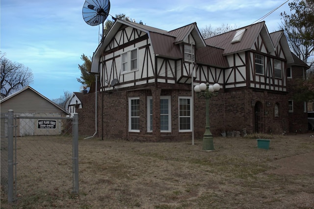 view of home's exterior featuring metal roof, brick siding, fence, stucco siding, and a standing seam roof