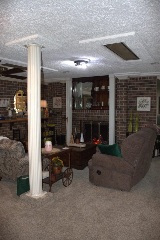 carpeted living room with a textured ceiling, brick wall, a brick fireplace, and ornate columns