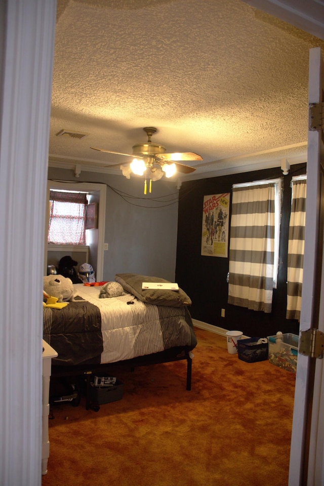 bedroom featuring carpet floors, visible vents, ceiling fan, and a textured ceiling