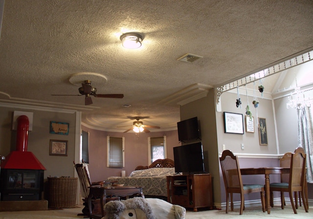 dining space with crown molding, visible vents, a ceiling fan, a wood stove, and a textured ceiling