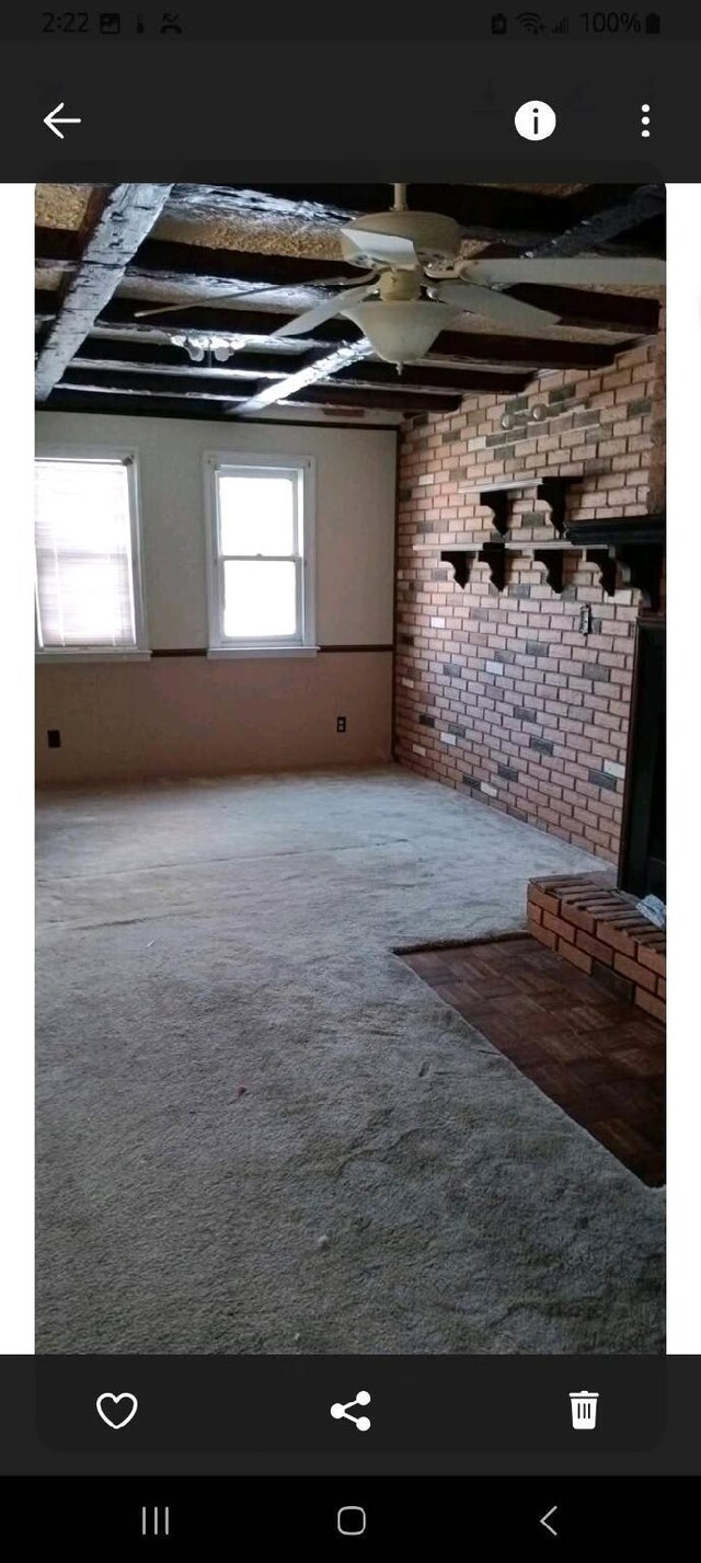 interior space featuring brick wall, beamed ceiling, and carpet flooring