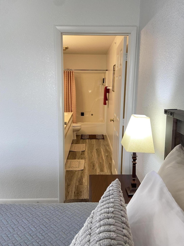 bedroom with ensuite bathroom and hardwood / wood-style floors