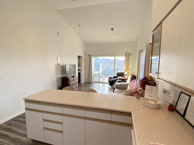 kitchen with white cabinets, high vaulted ceiling, dark wood-type flooring, and kitchen peninsula