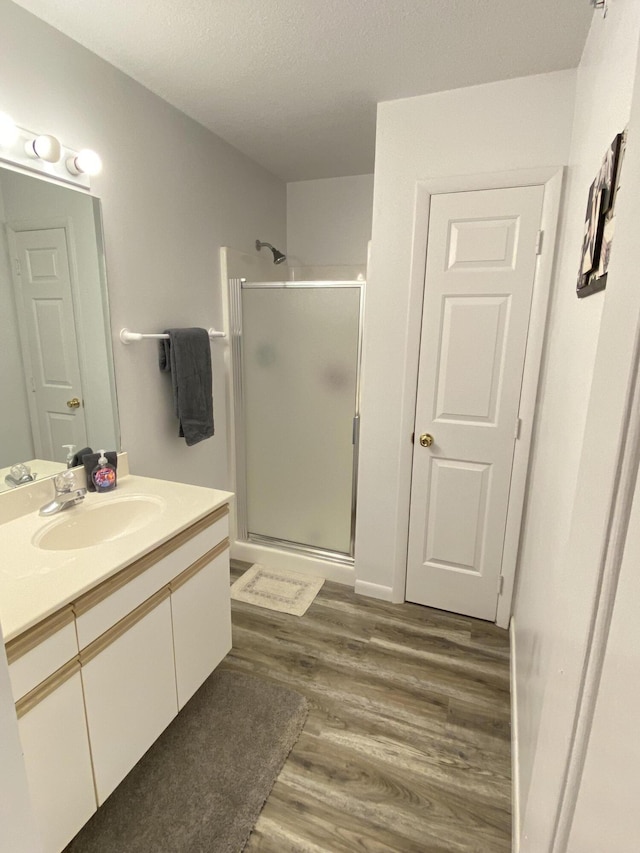 bathroom with vanity, a shower with door, a textured ceiling, and hardwood / wood-style floors