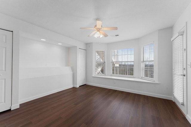 empty room featuring ceiling fan, dark hardwood / wood-style floors, and a healthy amount of sunlight