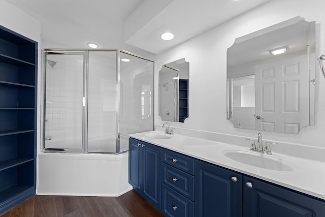 bathroom with hardwood / wood-style floors, combined bath / shower with glass door, and vanity