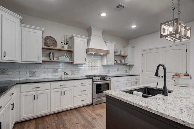 kitchen featuring stainless steel gas stove, sink, custom range hood, and white cabinets