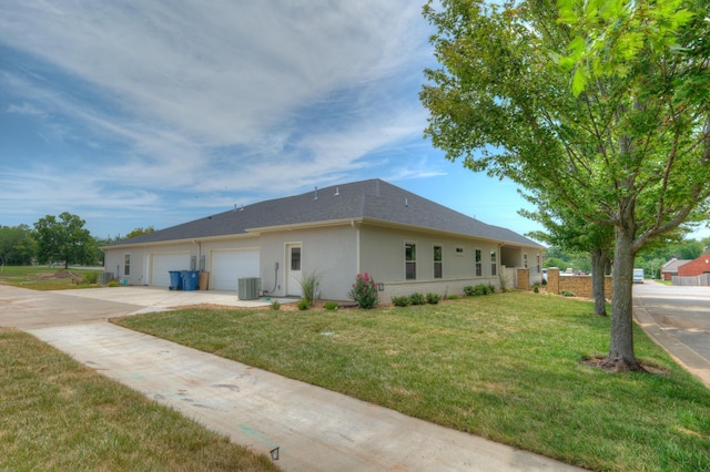 view of property exterior featuring central AC unit, a garage, and a lawn