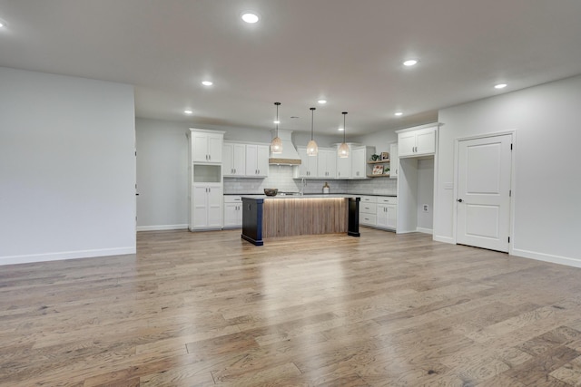 kitchen featuring white cabinets, a center island, hanging light fixtures, and light hardwood / wood-style flooring