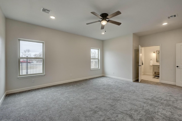 carpeted empty room with ceiling fan and connected bathroom