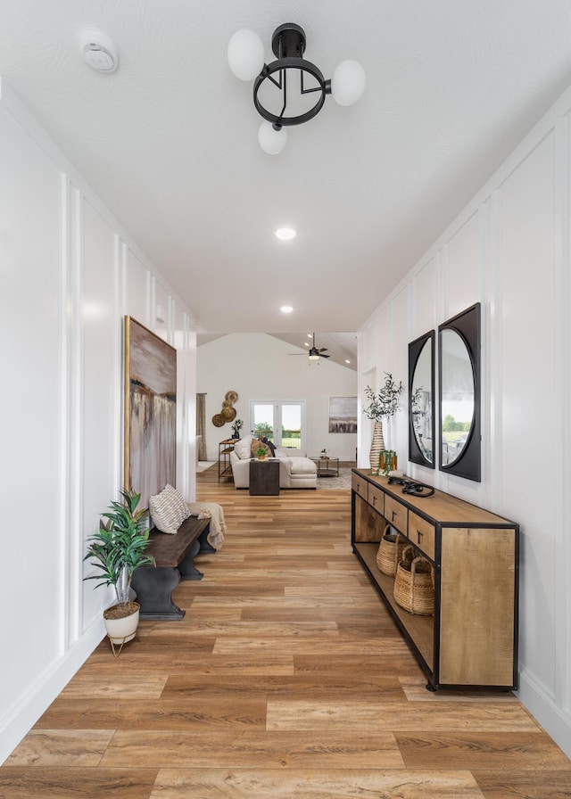 corridor with light hardwood / wood-style floors and vaulted ceiling