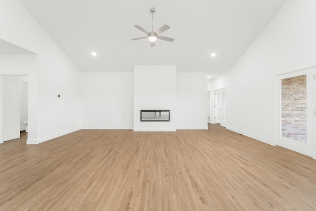 unfurnished living room with ceiling fan, light wood-type flooring, and high vaulted ceiling