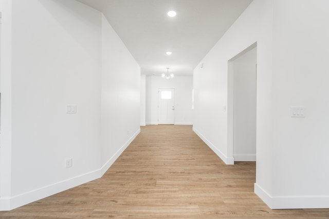 hallway featuring light wood-type flooring and a notable chandelier