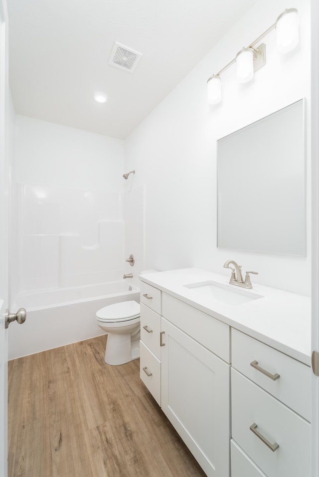 full bathroom featuring hardwood / wood-style floors,  shower combination, vanity, and toilet