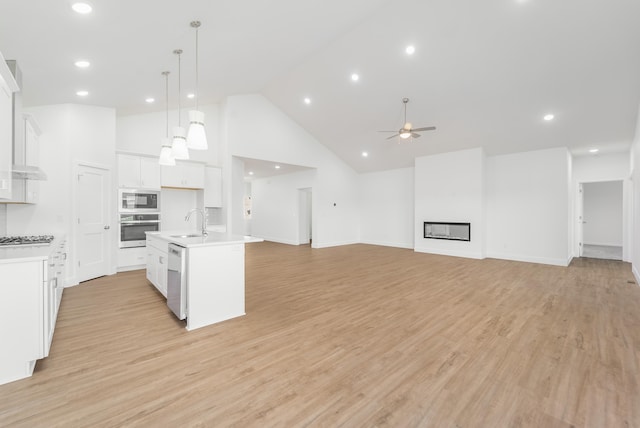 kitchen featuring a kitchen island with sink, decorative light fixtures, sink, appliances with stainless steel finishes, and white cabinets