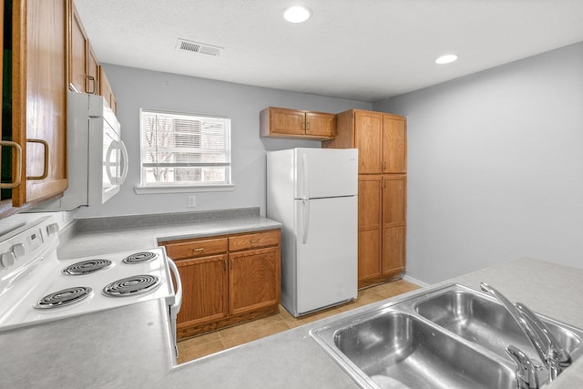 kitchen with white appliances, light tile patterned floors, sink, and a textured ceiling