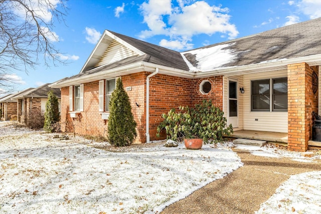 exterior space with brick siding and roof with shingles