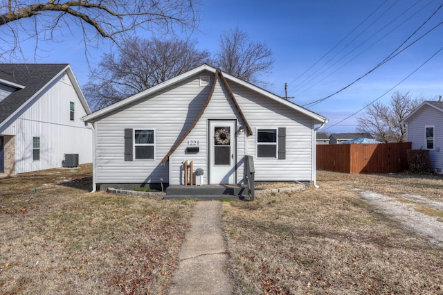 bungalow featuring a front lawn, fence, and central air condition unit