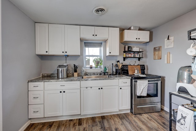 kitchen with electric stove, white cabinets, a sink, and visible vents