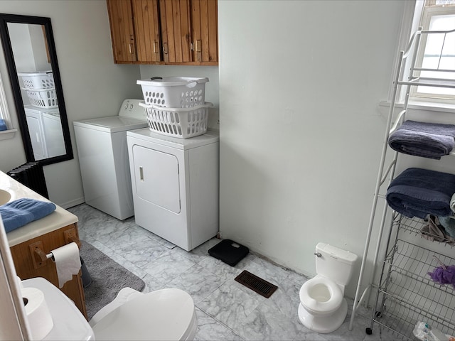 clothes washing area with marble finish floor, washing machine and clothes dryer, and laundry area