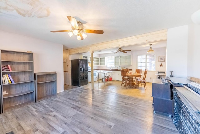 living room featuring light wood-style floors, a textured ceiling, and a ceiling fan