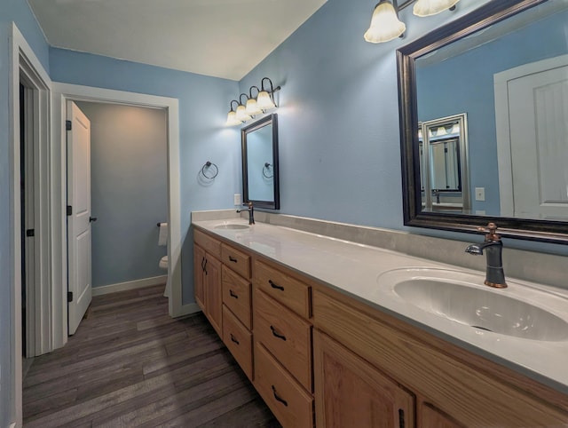 full bath with double vanity, toilet, a sink, and wood finished floors