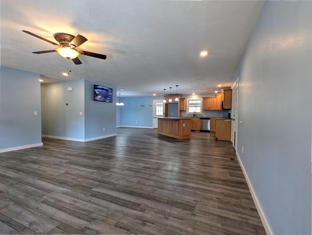 unfurnished living room featuring a sink, ceiling fan, baseboards, and dark wood-style flooring