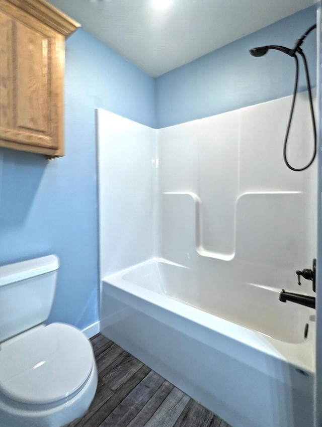 bathroom featuring toilet, washtub / shower combination, and wood finished floors