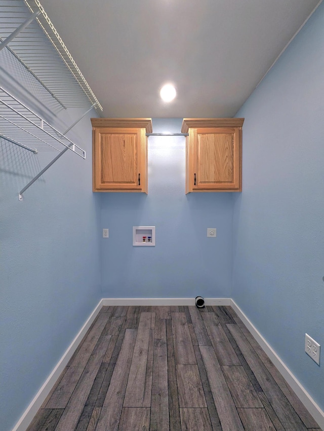 washroom with dark wood-type flooring, hookup for a washing machine, cabinet space, and baseboards