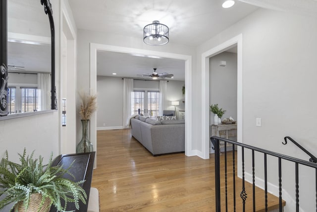 hall featuring an inviting chandelier, light wood-style flooring, baseboards, and recessed lighting