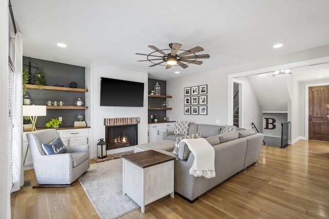 living room featuring ceiling fan, recessed lighting, a fireplace, stairs, and light wood finished floors