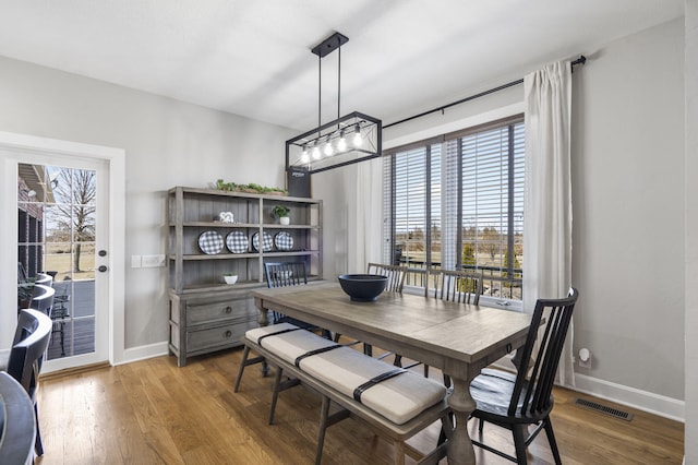 dining space with light wood-type flooring, visible vents, and baseboards