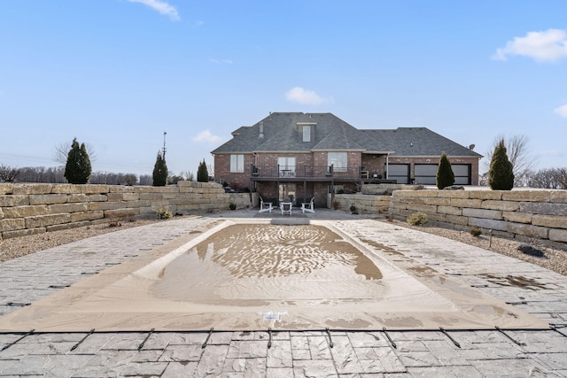 back of house featuring driveway, a patio area, and brick siding