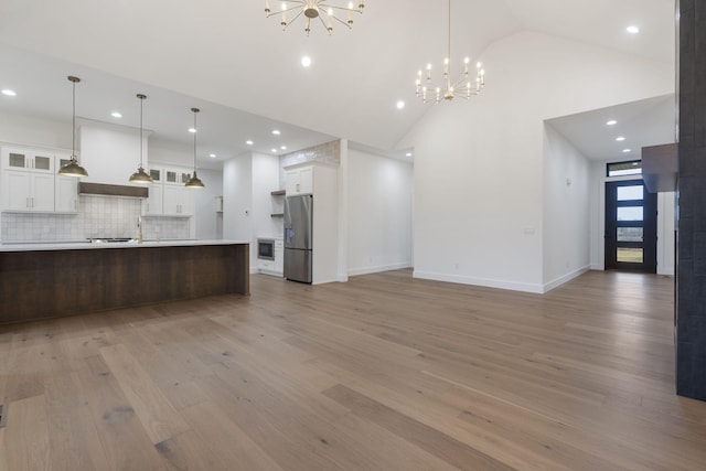 kitchen with stainless steel refrigerator with ice dispenser, light countertops, glass insert cabinets, open floor plan, and white cabinets